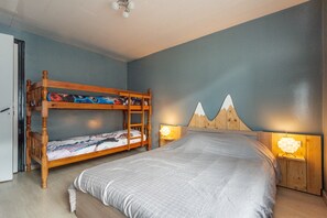 Un dormitorio con una cama litera, una cama individual y dos lámparas de noche.