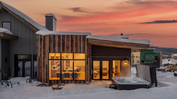 A modern building with large windows and a hot tub in the snow.