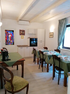 A dining area with a wooden table set for four, a coffee maker, and a stained glass window.