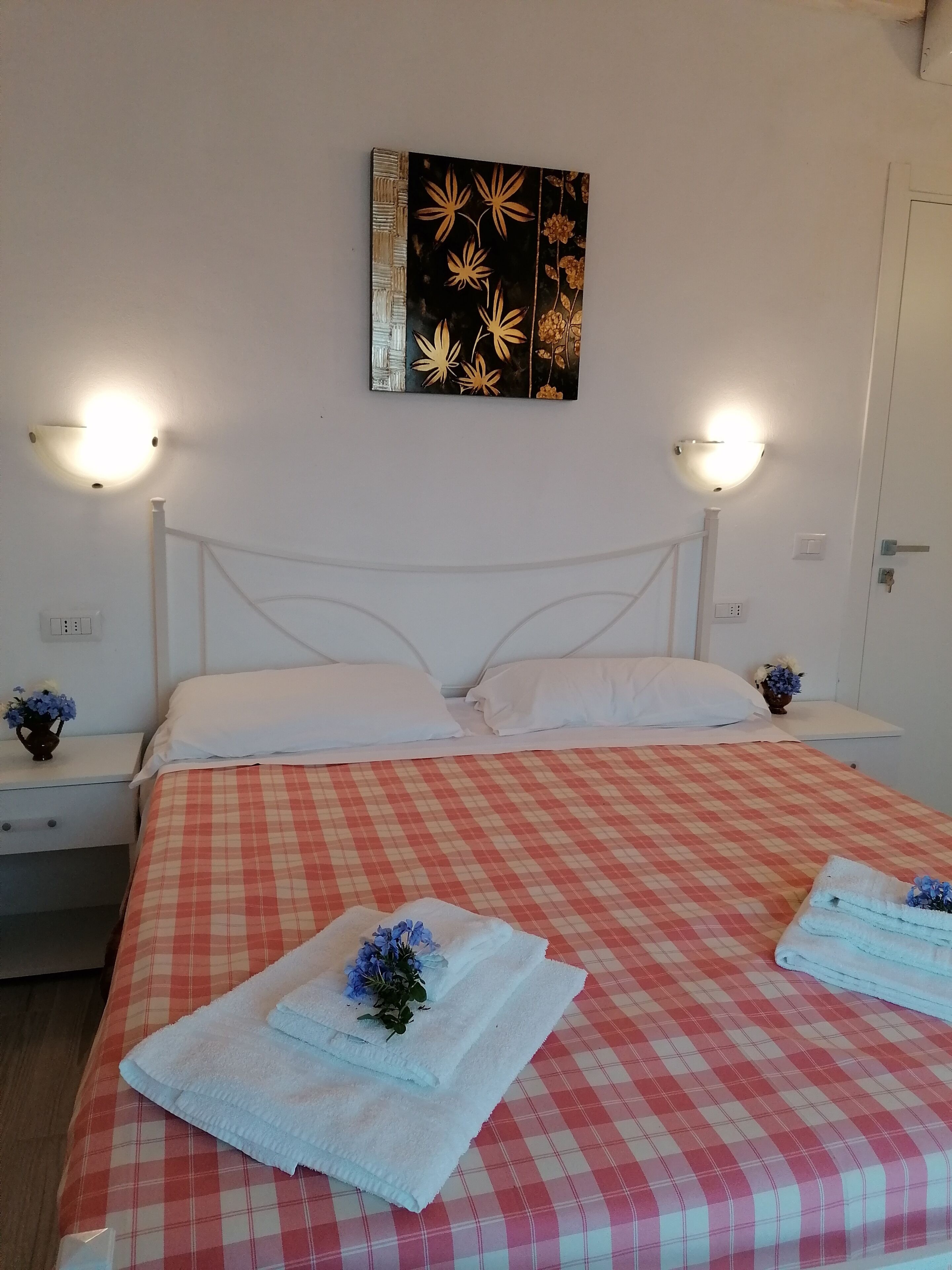 A neatly made bed with a checkered bedspread, two white pillows, and a decorative wall piece above it.