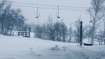 A snowy landscape with a wooden bench and a lamp post.