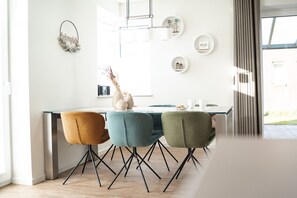 A modern kitchen with a dining area, featuring a central island, pendant lighting, and a view of the outdoors.