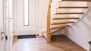 A modern staircase with wooden steps and white railings, leading to a door with a window.