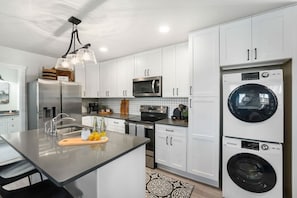 A modern kitchen with white cabinets, stainless steel appliances, and a central island with a cutting board and lemons.