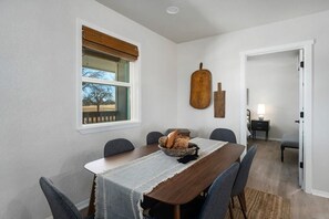 Ein Essbereich mit einem Holztisch, Stühlen und einem Fenster mit Blick auf Bäume.