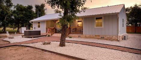 A two-story building with a covered porch and a hot tub.