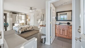 Une chambre d’hôtel moderne comprenant un lit, un coin salon, une kitchenette et une salle de bain.