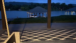 Une terrasse couverte avec un sol à motifs, donnant sur un lac agrémenté d’un belvédère et d’un quai.