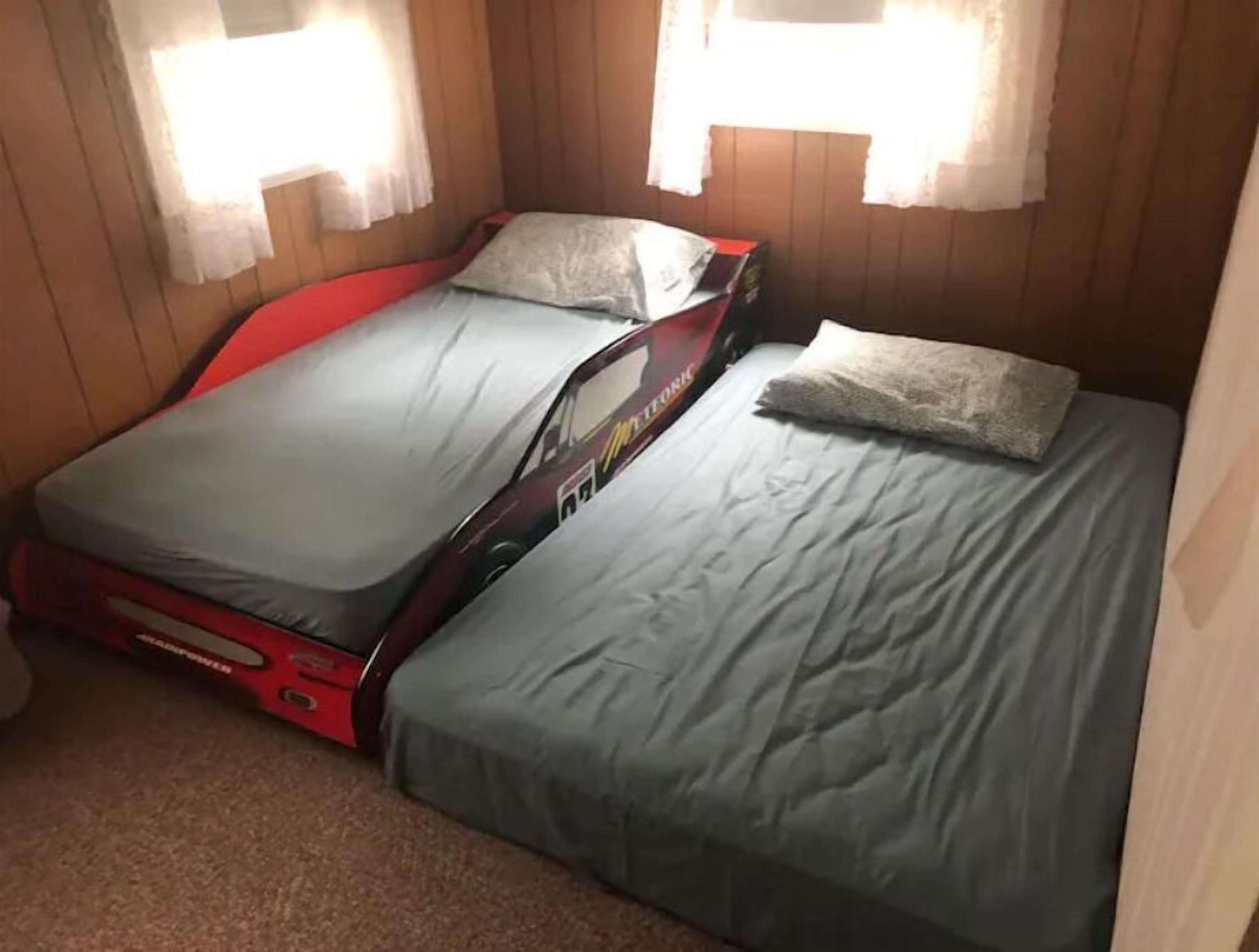 A compact room with a bed and a red suitcase.