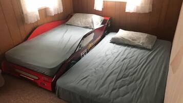 A compact room with a bed and a red suitcase.