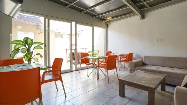 A spacious living area with a sofa, coffee table, and orange chairs around a glass table. - İpek Otel (Balikesir)