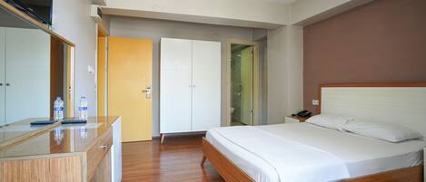 Una habitación de hotel moderna con una cama de madera, un escritorio con televisor de pantalla plana y un armario.
