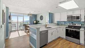 A modern kitchen with a large island, stainless steel appliances, and a view to the outside.