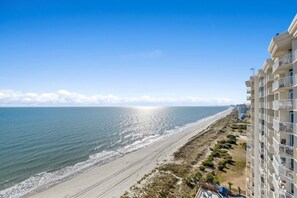 A coastal view with a beach and a high-rise building.