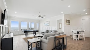 A spacious living room with a pool table, a sofa, a dining table, and a ceiling fan. - The Beach Club 8BR OF House in Cherry Grove (North Myrtle Beach)