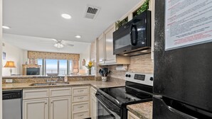 A modern kitchen with a black refrigerator, stainless steel appliances, and beige cabinetry. - Carolina Dunes 502 2BR OF Condo in Cherry Grove (North Myrtle Beach)