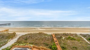 A beach view with a wooden boardwalk leading to a pier. - Carolina Dunes 502 2BR OF Condo in Cherry Grove (North Myrtle Beach)