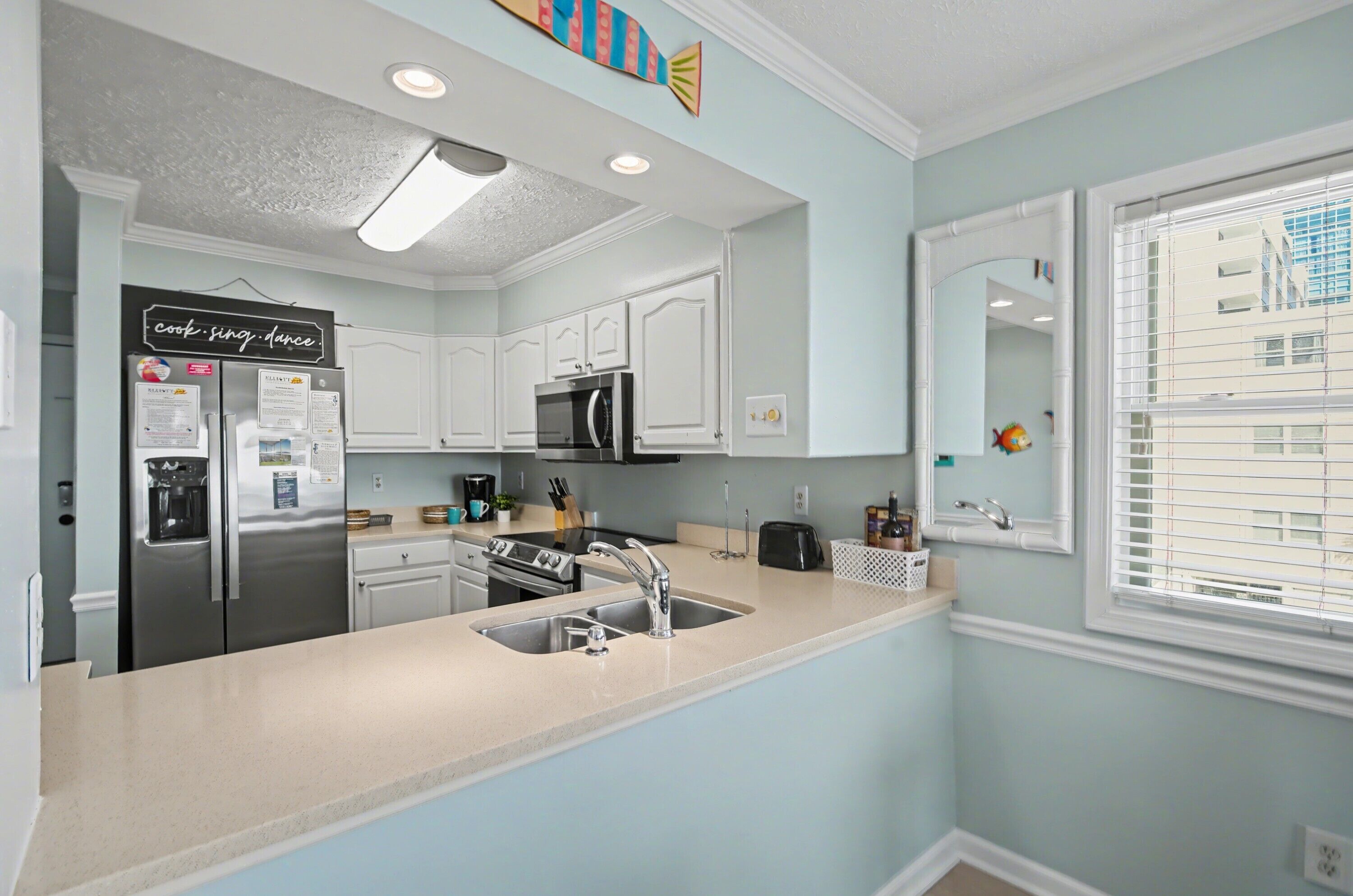 A modern kitchen with a stainless steel refrigerator, a microwave, and a sink.