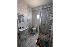 Bathroom features a sink, mirror, toilet, and shower with a glass door.