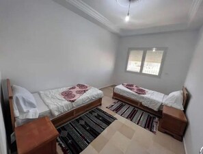Two single beds with wooden frames and white bedding, set against a simple, clean design.