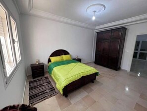 Relax in this serene bedroom with a large bed, a bedside table, and a ceiling fan.