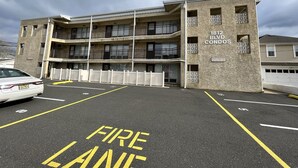 A multi-story building with balconies, labeled "1812 BLVD. CONDOS," and a parking lot with "FIRE LANE" markings. - Perfect Getaway. Only 1 block to the Beach (Seaside Park)