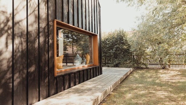 Un edificio moderno con fachada de madera y una ventana con marco de madera.