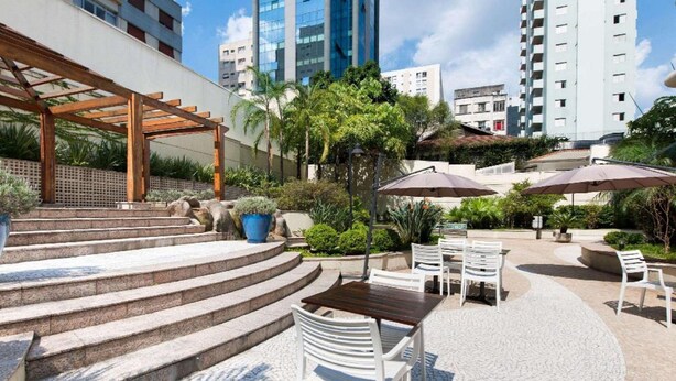 A courtyard with outdoor seating, steps leading to a covered area, and modern buildings in the background. - Elegance Suites Oscar Freire (São Paulo)