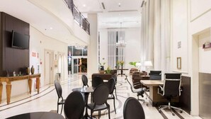 A spacious lobby with a reception desk, seating area, and a staircase. - Elegance Suites Oscar Freire (São Paulo)