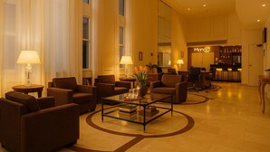 A spacious lobby with multiple seating areas, a reception desk, and a bar. - Elegance Suites Oscar Freire (São Paulo)
