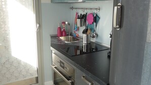 A modern kitchen with stainless steel appliances, a built-in oven, and a window with frosted glass.