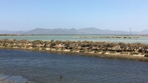 A coastal landscape with a clear view of the sea and distant mountains.
