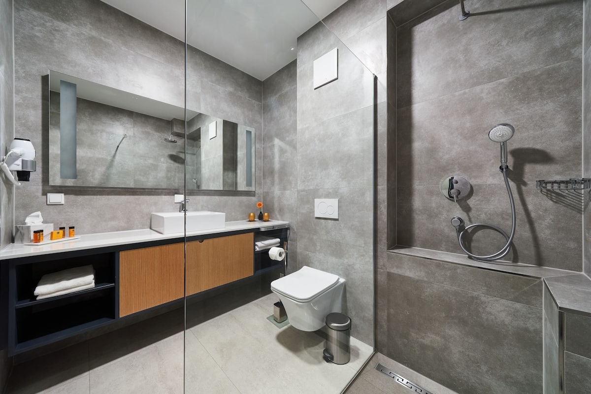 Ein modernes Badezimmer mit großem Spiegel, Toilette, Waschbecken und Duschbereich.