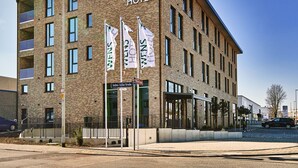A modern hotel building with a prominent 'WEN'S HOTEL' sign, multiple windows, and flags. - WENS Hotel (Mainz)