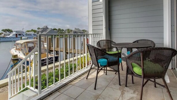 A balcony with a table and chairs, overlooking a marina with boats. - Beautiful marina views, manatees and private beach in the Moorings of Vero!  (Vero Beach)