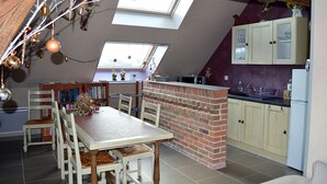 Cocina estilo loft con una isla de ladrillo, tragaluces y un comedor con sillas y mesa de madera.