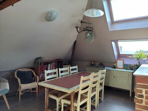 Un comedor con mesa y sillas, un reloj en la pared y un ventanal con vistas.