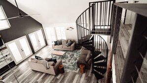 Una sala de estar moderna con una escalera en espiral, un juego de sofá y un tapete estampado.