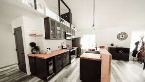 Una cocina moderna con armarios negros, encimera de madera y una isla central.