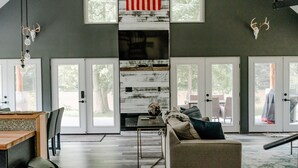 Una sala de estar moderna con chimenea, un comedor y ventanas amplias.