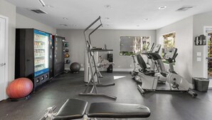 A gym with exercise equipment, a vending machine, and a large exercise ball.