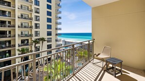A balcony with a view of the ocean, a chair, and a pool area. - Origin 0808 - One Bedroom - Sunny Pool Deck & Gulf Views! (Panama City Beach)