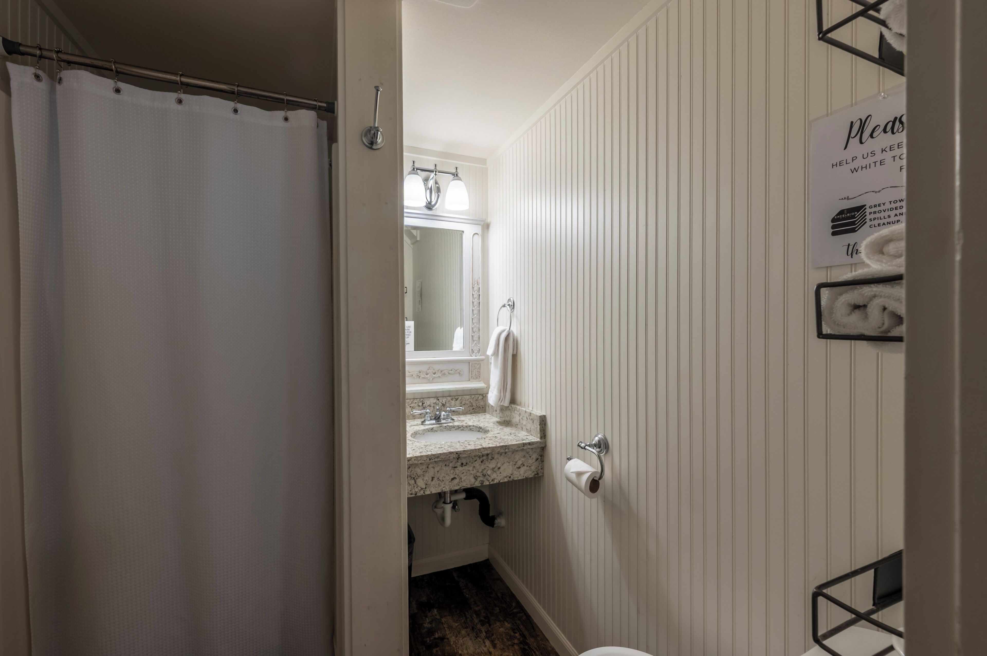 A bathroom with a shower curtain, a sink with a mirror, and a toilet.