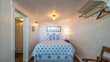 Un dormitorio con cama, ventana, mesita de noche y una silla.