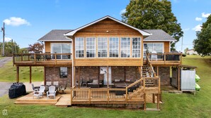Une maison en bois à deux étages, dotée d’un balcon, d’un espace extérieur aménagé pour s’asseoir et d’une terrasse couverte.