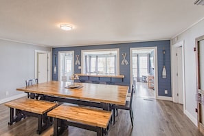 A spacious dining area with a long wooden table, benches, and a kitchen area in the background. - The All Seasons Resort: Pool, Hot Tub,  & Private Dock (Georgetown)