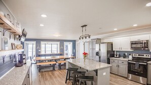 Une cuisine moderne dotée de plans de travail en granit, d’appareils électroménagers en acier inoxydable et d’un îlot central avec des tabourets de bar.