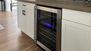 Un four en acier inoxydable intégré dans une cuisine dotée de meubles blancs et d’un pare-feu décoratif.
