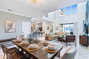 A spacious living area with a dining table set for six, a sofa, and a television. - Pool, Themed Rooms & Man Cave! 5BR Oasis (Kissimmee)