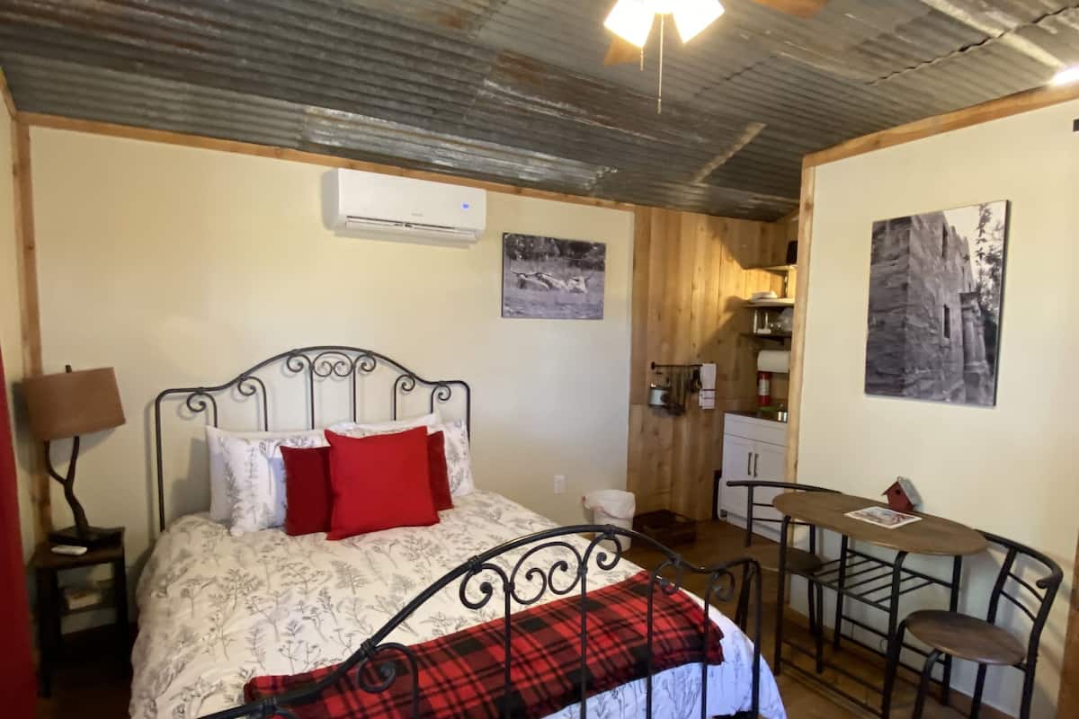 A bedroom with a bed, a desk, and a chair.